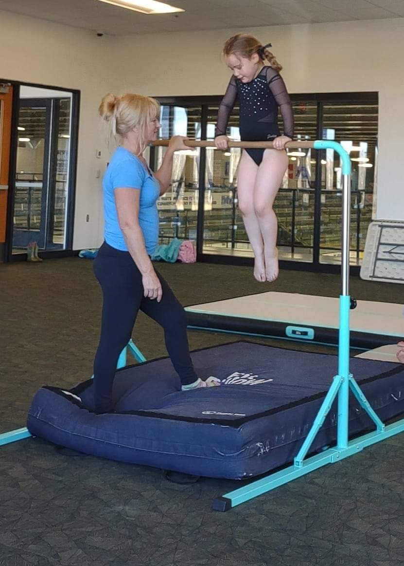 Image of Brittany coaching a student on bar